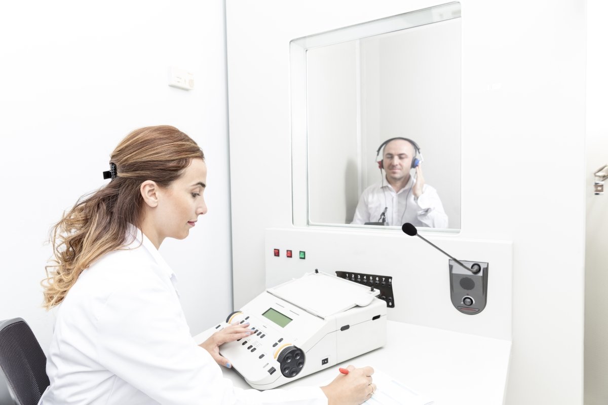 audiologist performing a hearing test with client in booth
