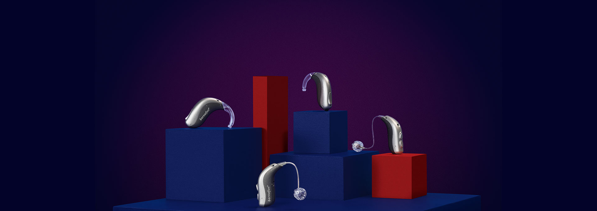 4 aides auditives Bernafon Alpha (miniBTE T R, miniRITE T R, miniBTE T, miniRITE T) sur des cubes rouges et bleus à fond violet