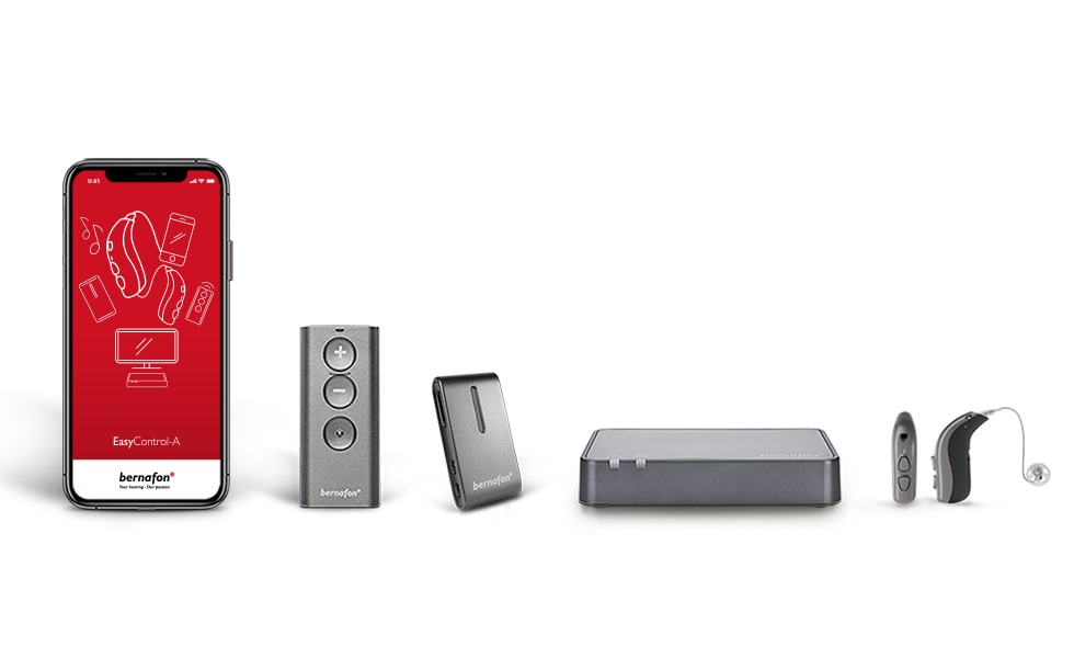 Les accessoires Bernafon sont alignés, y compris l'application Bernafon sur un smartphone, l'adaptateur TV, la télécommande, les appareils auditifs et le SoundClip-A.