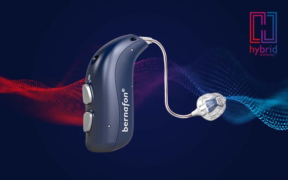 Appareil auditif rechargeable Bernafon Alpha bleu nuit avec le logo de la technologie hybride et une onde sonore rouge/bleue à l'arrière.