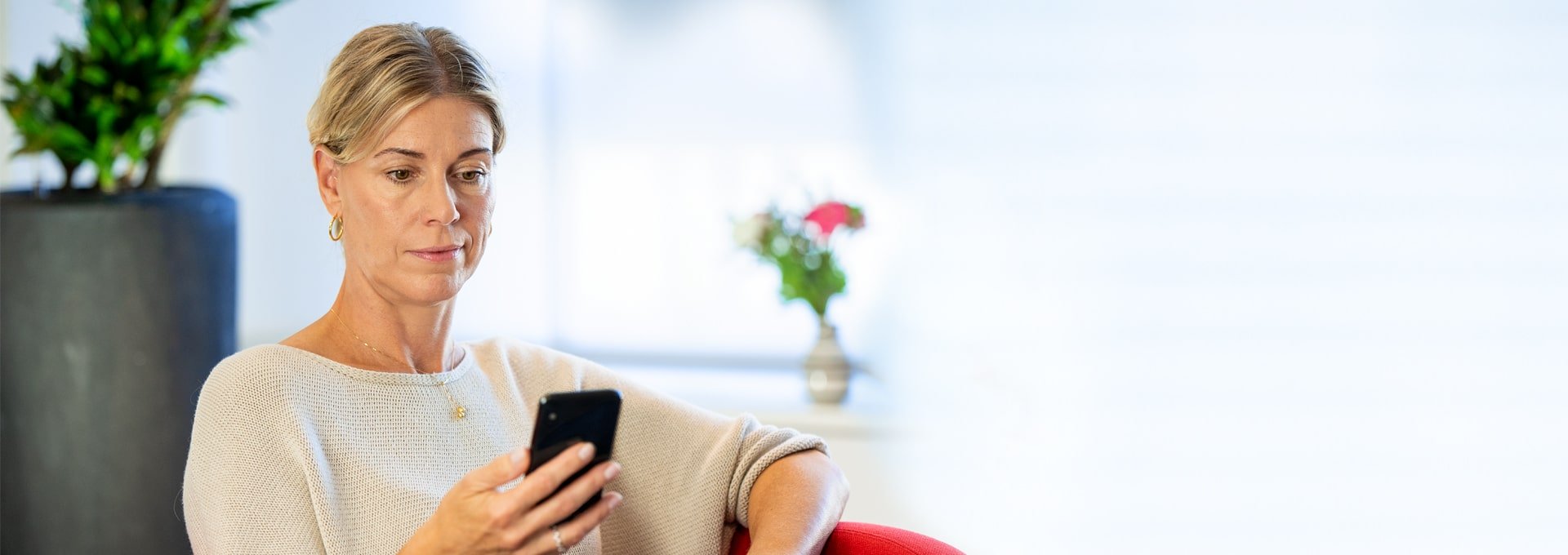 Femme souriante et détendue regardant son smartphone.