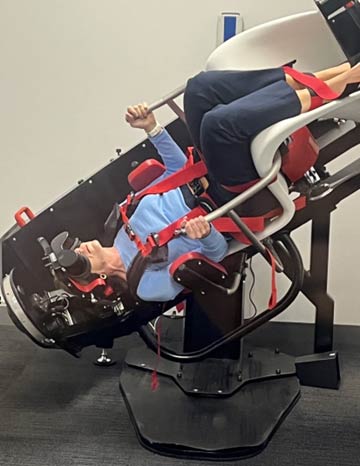 Women strapped into TRV chair and vertical