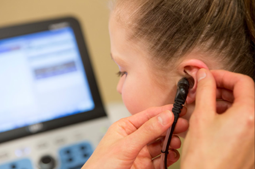 An audiologist inserting a tympanometry probe in a patient's ear