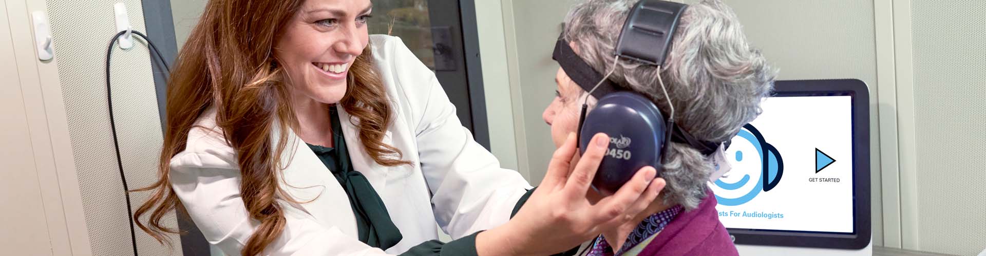 An audiologist setting up a patient for automated audiometry testing