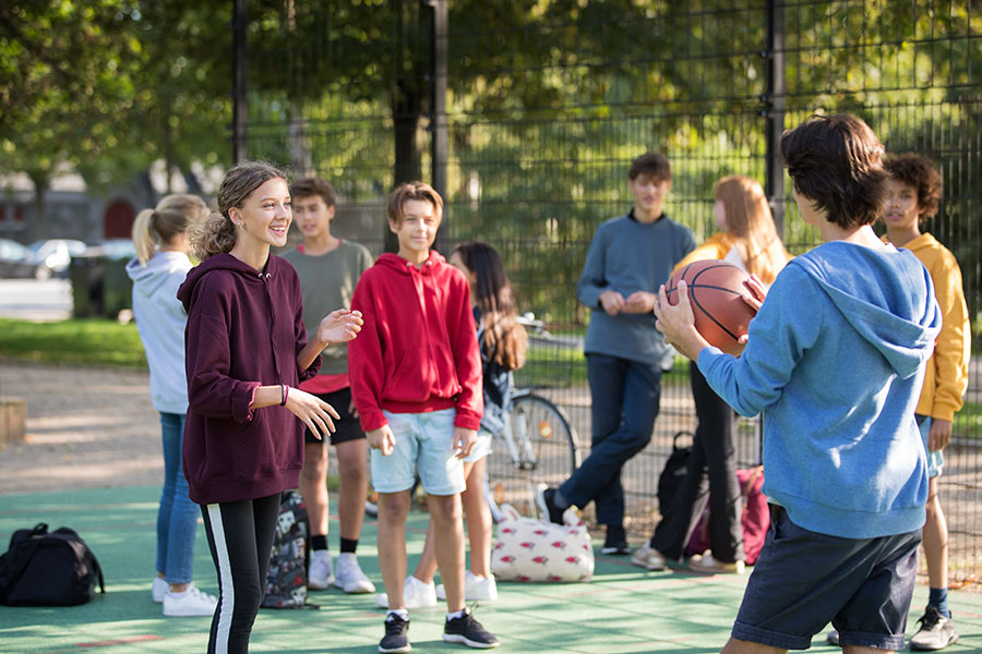 Teen wearing opn play hearing aids playing basketball